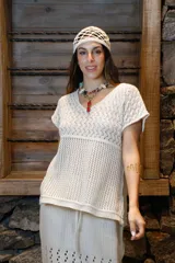 Remera tejida color crudo con hilo de algodón en punto calado, escote en V, manga corta, silueta oversize y tajos laterales.