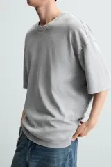 Camiseta azul marino de corte holgado, confeccionada en algodón con cuello redondo y mangas cortas. Presenta un efecto de lavado que le da una apariencia única.