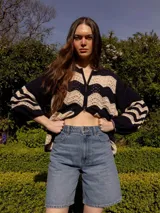 Campera de tejido de punto con cierre frontal, diseño a rayas horizontales en colores negro y beige.