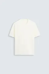Camiseta color crema de punto con hilatura de mezcla de algodón, corte relaxed fit, cuello redondo y manga corta con terminaciones en rib.