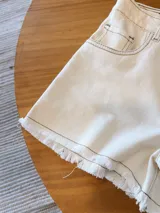 Short de jean color beige con terminación desflecada.