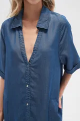 Vestido largo camisero de lyocell azul denim, corte holgado, con cuello camisero, mangas cortas con dobladillo y cierre frontal con botones.