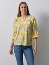 Blusa de gasa verde con estampado de flores blancas y celestes. Tiene cuello a la base con escote en V y mangas 3/4 fruncidas.