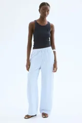 Pantalón de corte holgado en tejido liviano de mezcla de lino a rayas verticales celestes y blancas. Modelo de tiro alto con cintura elástica y cordón para ajustar fino, bolsillos laterales discretos y piernas rectas.