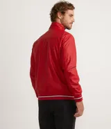 Chaqueta bomber roja de poliéster engomado, con cuello, puños y cintura acanalados a rayas blancas y azul marino. Tiene cierre frontal con cremallera y bolsillos laterales con cremallera.