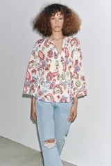 Camisa de algodón color crudo con estampado de cachemir en tonos rojo, azul y verde. Tiene cuello redondo, escote en pico, manga tres cuartos acampanada y bajo asimétrico redondeado.