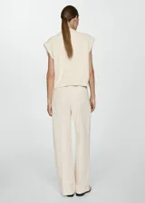 Pantalón de vestir color crema, de corte recto y tiro alto, con pinzas delanteras, bolsillos laterales y cierre oculto.
