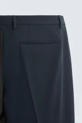 Pantalón de vestir color verde oliva, corte slim fit, con bolsillos laterales y traseros de ojal con botón. Cierre frontal con cremallera y botón.