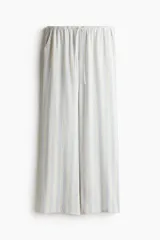 Pantalón de tiro bajo con elástico y cordón ajustable en la cintura, bolsillos al bies y piernas rectas. Confeccionado en tejido liviano con lino en la trama y estampado a rayas verticales en tonos celeste y beige.