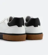 Championes urbanos blancos de cuero sintético con caña corta, recortes y suela tricolor texturizada.