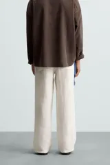 Pantalón de lino color blanco, de corte regular fit. Presenta cintura elástica, bolsillos frontales y traseros de plastrón, con cierre frontal de cremallera y botón.