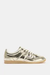 Zapatillas deportivas doradas con efecto metalizado. Cierre con cordones y suela de goma color caramelo.