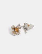 Aros pasantes con forma de flor, con centro dorado y pétalos plateados. Cierre de tope a presión.