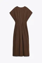Vestido midi color marrón confeccionado en hilatura con mezcla de algodón y lino. Tiene cuello redondo, manga corta caída y detalle de pliegues en la cintura. Cierre en la espalda con abertura y botón.