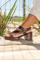 Sandalias negras de cuero con plataforma y taco cuadrado. Tiras cruzadas sobre el empeine y hebilla metálica lateral.