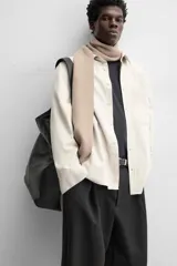 Camisa color crema de corte relaxed fit, confeccionada en tejido de mezcla de algodón suave al tacto. Tiene cuello solapa, manga larga con puños abotonados, un bolsillo de parche en el pecho y cierre frontal con botones.