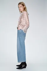 Jeans de tiro alto con pernera ancha y corte cropped. Presenta diseño de cinco bolsillos, cierre frontal con cremallera y botón, e incluye un cinturón a juego.