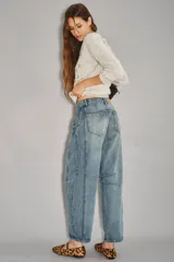 Jean de denim rígido azul claro, tiro medio-alto, con calce holgado y piernas anchas que se estrechan ligeramente hacia el tobillo. Presenta pinzas en la zona de las rodillas y un recorte en el lateral.