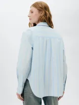 Camisa celeste con rayas verticales blancas, de manga larga y corte clásico.