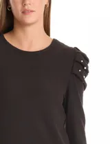 Buzo negro de tejido suave, marca Zac & Rachel, con cuello a la base y manga larga. Presenta hombros plisados y decorados con perlas.