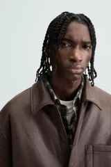 Sobrecamisa marrón de efecto piel con interior de borreguillo a tono, de corte relaxed fit, cuello solapa, manga larga con puños abotonados, bolsillos de plastrón en pecho y laterales, efecto lavado y cierre frontal con botones a presión.