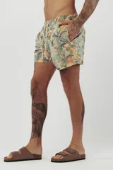 Short de baño con estampado de hojas de palmera en tonos beige, verde y naranja.