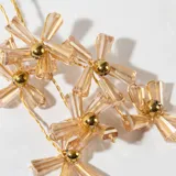Aros colgantes con forma de flores color champagne y detalles dorados.