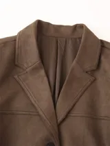 Blazer marrón de gamuza con cuello de solapa, cierre con botones y bolsillos frontales.