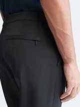 Pantalón chino de corte slim color negro, con bolsillos laterales y traseros, cierre con cremallera y botón, y trabillas para cinturón.