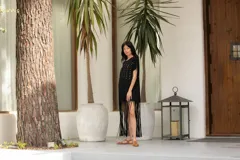 Vestido negro de algodón con corte recto, cuello redondo, mangas cortas, tachas plateadas en el frente y flecos largos en el ruedo.