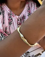 Brazalete rígido abierto de bronce con textura irregular.