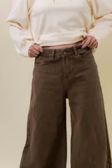 Pantalón de denim color marrón, de tiro medio-alto y calce wide leg con pierna amplia.