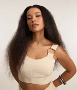 Blusa cropped de sastrería color beige, con escote corazón, breteles anchos con aros metálicos y cierre en la espalda.