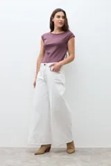 Pantalón de jean blanco crudo de tiro alto, corte culotte ancho y largo, con costuras en color rojizo.