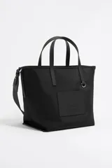 Bolso shopper mediano Bimba y Lola color negro, con doble asa de mano y correa bandolera ajustable y extraíble. Presenta un parche rectangular con el logo de la marca en la parte frontal.