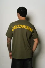 Remera verde oliva de corte regular fit, confeccionada en jersey de algodón. Presenta un pequeño logo bordado en el pecho y un estampado grande con el nombre de la marca en la espalda, ambos en color amarillo.