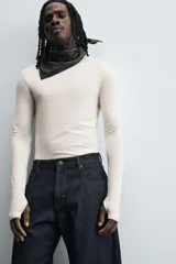 Camiseta de manga larga color crudo, corte ajustado y cuello redondo. Tiene aberturas en los puños y efecto lavado.