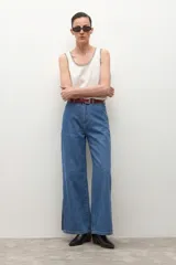 Pantalón de jean de tiro alto, color azul medio, con corte ancho y recto, y aberturas laterales en el ruedo.