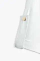 Camiseta blanca de algodón con cuello redondo y mangas cortas con vuelta, trabilla y botón.