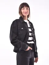 Campera de jean negra, estilo trucker, con cuello camisero, botones metálicos y bolsillos frontales con tapa.