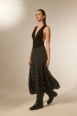 Falda larga de poliéster, color negro con estampado de lunares blancos. Corte amplio y fluido.