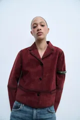 Blazer color borgoña confeccionado en piel de ante. Tiene cuello solapa de muescas, manga larga, bolsillos de vivo en delantero, forro interior y cierre frontal con botones.