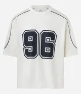Remera de corte boxy color crema con estampa del número 96 en el frente y detalles en negro en cuello y mangas.