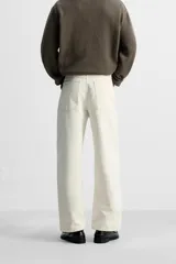 Pantalón de jean color crudo, corte amplio y tiro alto, con cinco bolsillos y cierre frontal con botones.