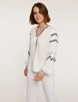 Blusa blanca de manga larga con bordados negros en cuello, mangas y frente.