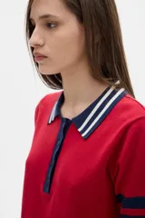Remera polo corta color rojo con cuello y mangas con rayas azul marino y blanco.