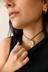 Collar con tiento encerado negro y dije dorado con forma de corazón texturizado.