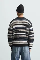 Sweater de punto con cuello redondo y manga larga, con diseño de rayas horizontales en tonos negro, gris y blanco.