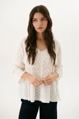 Camisa blanca con bordado floral, cuello en V y cierre frontal con botones.
