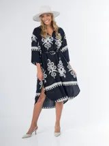 Vestido midi oversized de origen italiano, con estampado en fondo negro o crudo, cuello tipo camisa, escote en V y tajos laterales.